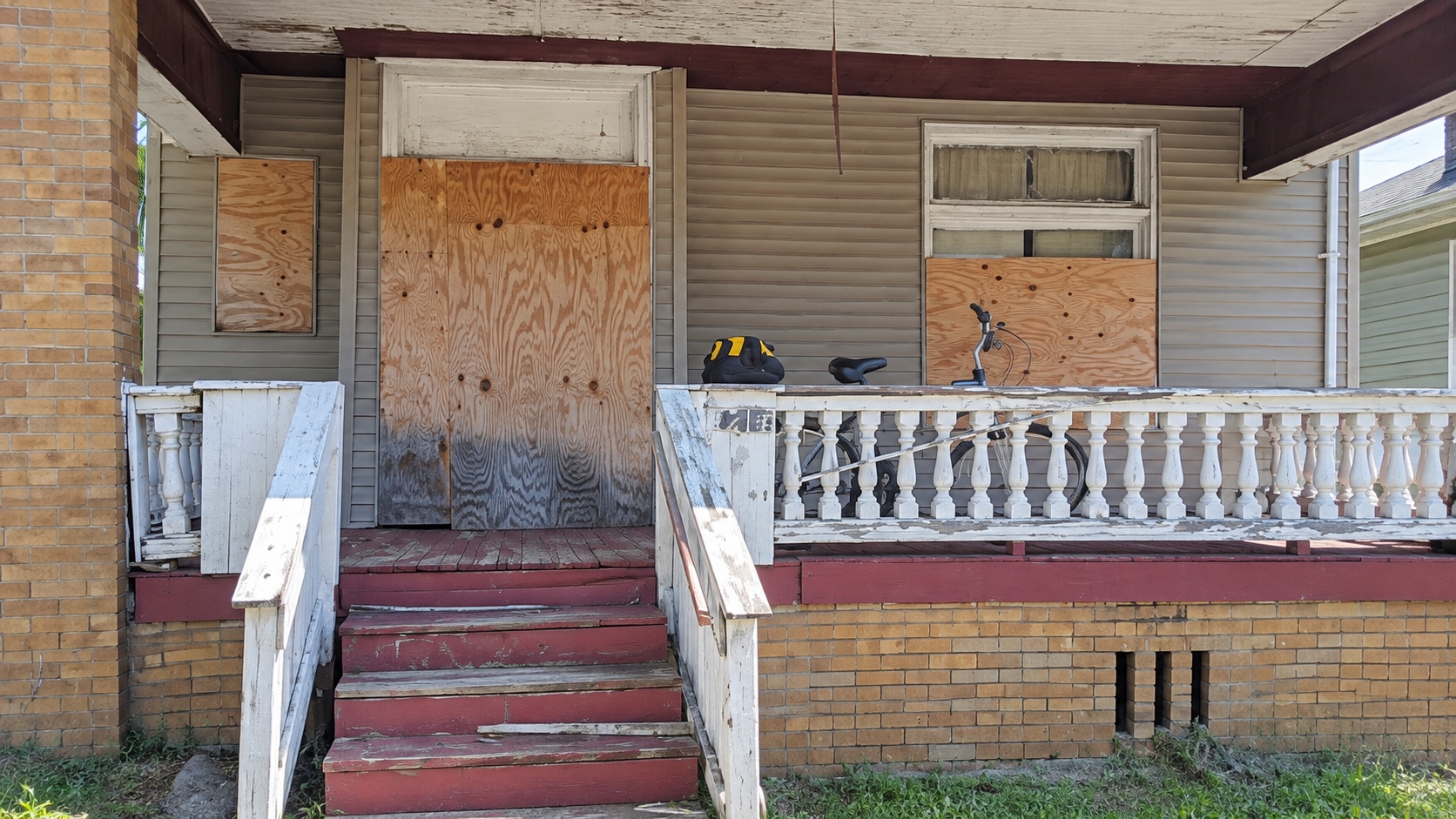 AI-assisted reframed current-condition front porch and boarded openings